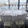 Round timber table hire with white chairs and a view of the city.