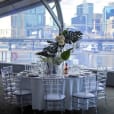 A table set up with clear Tiffany chairs and a view of the city.