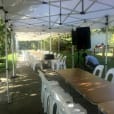 A backyard set up with timber trestle tables and chairs for hire.