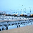 White tables and chairs, including Timber Trestle Table 2.4m Hire, are set up in front of a tent.