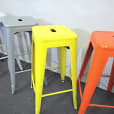 A row of vibrant yellow Tolix stools.