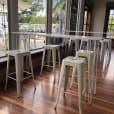 In a trendy restaurant, elegant white stools gently punctuate the warm wooden floor.