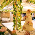 A large wedding cake is sitting on a table in a room filled with flowers.