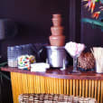 A table with a chocolate fountain and a vase of assorted lollies.