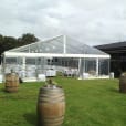 A 6m x 39m white tent set up in a grassy area with wine barrels.