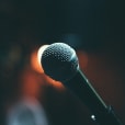 A close up of a corded microphone in front of a blurred background.