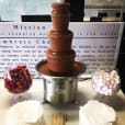 A Small Commercial chocolate fountain on a table in a conference room.