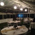 A tent with tables and chairs set up for a wedding reception, adorned with elegant white rice lanterns.