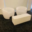 Two white chairs and a white ottoman in a room available for Glow Couch Hire.