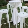 A set of white Tolix stools in a grassy area.