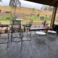 A white coffee table and chairs on a patio with a view of a field.