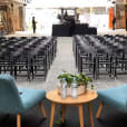 A room with black padded folding chairs and tables set up for a wedding.