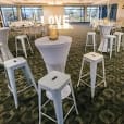A spacious room furnished with white Tolix stools and tables.