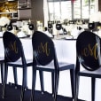 A table with black and white chairs and a Victorian-inspired monogrammed tablecloth.