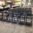 A row of black padded folding chairs in a lobby available for hire.