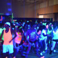 A group of people dancing in a gym with UV Black Light Hire, creating a stunning neon-lit atmosphere.