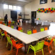 A room filled with tables and chairs for kids, adorned with colorful balloons.