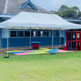 A white tent, specifically a 4mx8m Pop Up Marquee with a white roof, is set up in front of a building.
