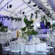 A large tent with Clear Tiffany Chair Hire set up on white tables.