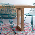 A dining table with turquoise blue chairs and a rug.