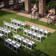 An outdoor wedding ceremony set up with white padded folding chairs.