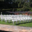 A row of white plastic chairs in a garden.