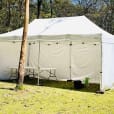 A 4mx8m pop-up marquee with walls set up in a grassy area.