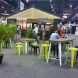 A booth at a trade show with tables and Lime Tolix stool hire.
