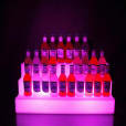 A hireable glow bottle shelf display with a vibrant purple light.