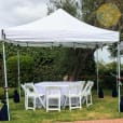 A white tent with a table and chairs, illuminated by Festoon Light Hire - 10m.