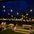 A deck with string lights and a view of the water illuminated by festoon light hire.