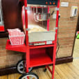 Red Popcorn Cart Hire sitting on a brick floor.