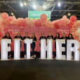 A group of people posing in front of a sign that says "fither" highlighted with glow letters.