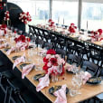 A black padded folding chair hire is set up for a wedding reception in a tent.