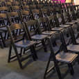 A row of black padded folding chairs in a room available for hire.