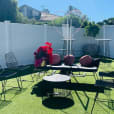 A backyard with black furniture and a white fence, featuring Black Wire Chair.