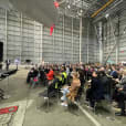 A large group of people attending a conference in a hangar.