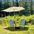 Two Deck Chairs under an umbrella in a grassy area.