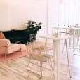 A pink and white room with a table, chairs, and a Gold Wire Stool.