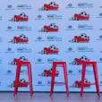 A group of red Tolix stools in front of a banner.