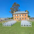 A wedding ceremony set up in front of a pristine white brick building.