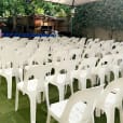 A large group of white plastic stackable chairs set up in an outdoor area.