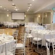 A large room with white tables and chairs available for White Tiffany Chair Hire.