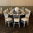 A white table and chairs set up in a room, available for White Tiffany Chair Hire.