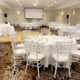 A large room with white tables and White Tiffany Chair Hire.