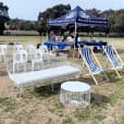 A group of white chairs and tables on a grassy field.