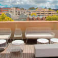 A balcony with white furniture, including a White Arrow 3 Seater Lounge Hire, and a view of the city.