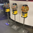 Three gumball machines stand in front of a wall.