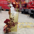 A red and gold flower arrangement in a warehouse with a gold mirror plinth.