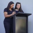 Two women standing in front of a lectern.